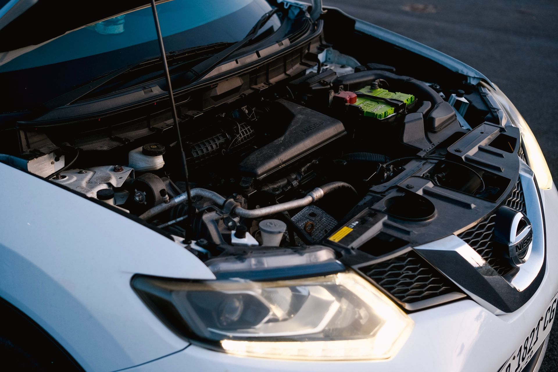 Close-up of a car engine with hood open, showcasing various mechanical components and details.